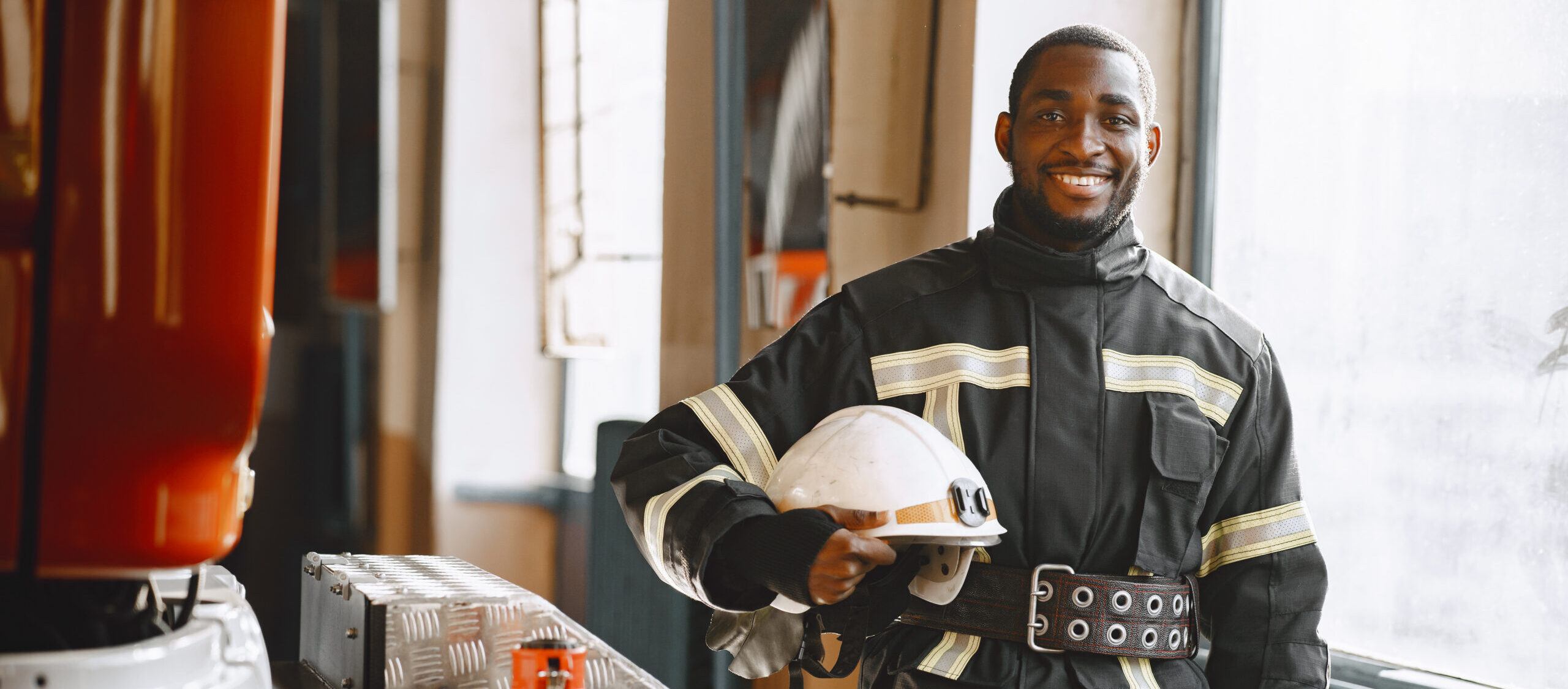 portrait of a firefighter standing next to firetruck in firestation